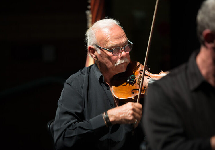 Man with grey hair playing violin